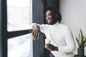 Cheerful black man looking out of window in cafeteria