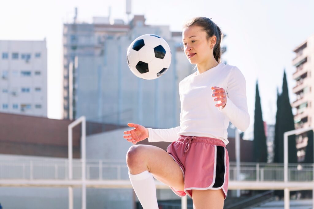 female soccer player kicking ball with her knee