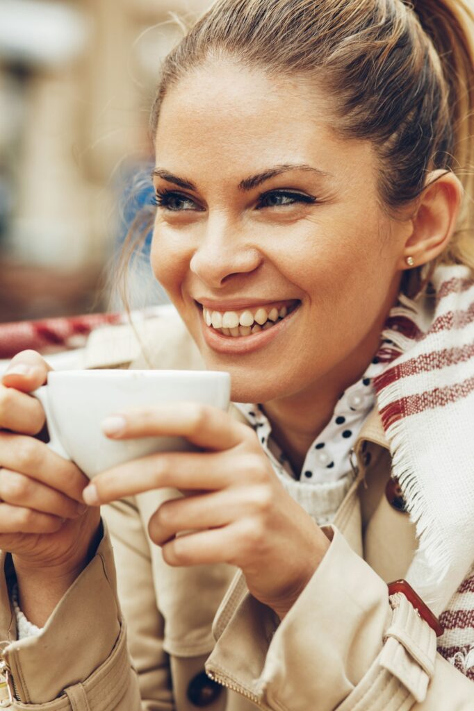 Happy woman enjoying a cup of coffee outdoors