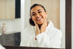 Happy woman in white bathrobe touching her cheeks