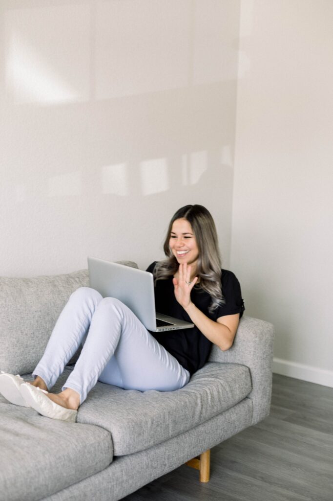 Hispanic young Woman sitting on couch while FaceTiming her family from her laptop