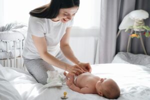 Mother and baby boy changing diaper after sleep.