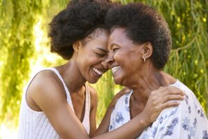 Multi-Generation Family With Senior Mother And Adult Daughter Laughing In Garden Together