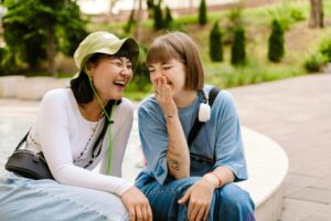 Multiracial two women talking and laughing while resting in park