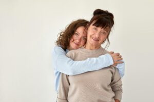 Young woman hugs mature smiling lady in casual clothing